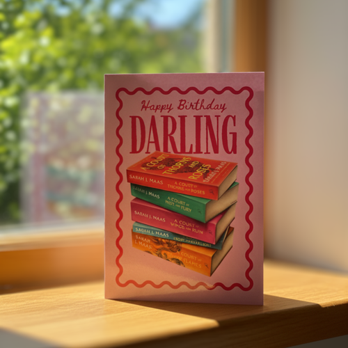 Birthday card with book stack design and ‘happy birthday darling’ text on a sunny windowsill