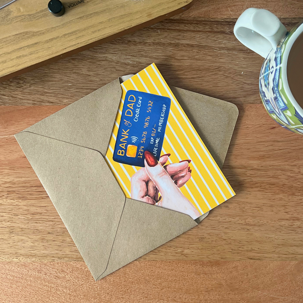 Father’s Day card tucked into an envelope on a wooden surface with a mug to the side.