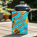 Birthday card for dad with barbecue-themed graphics on a blue striped background. Displayed on a garden table in front of a bbq