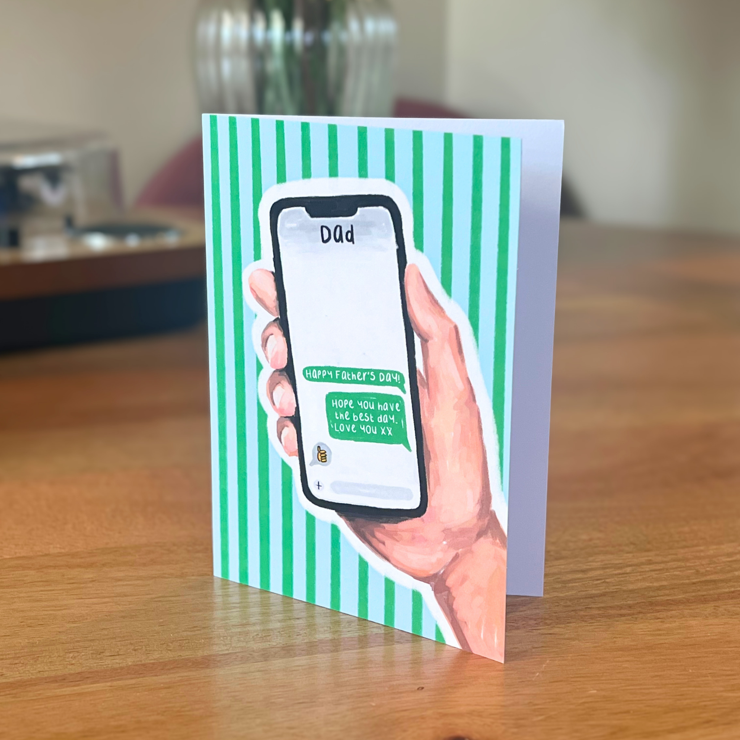Fathers day card with a hand holding a smartphone on a striped background