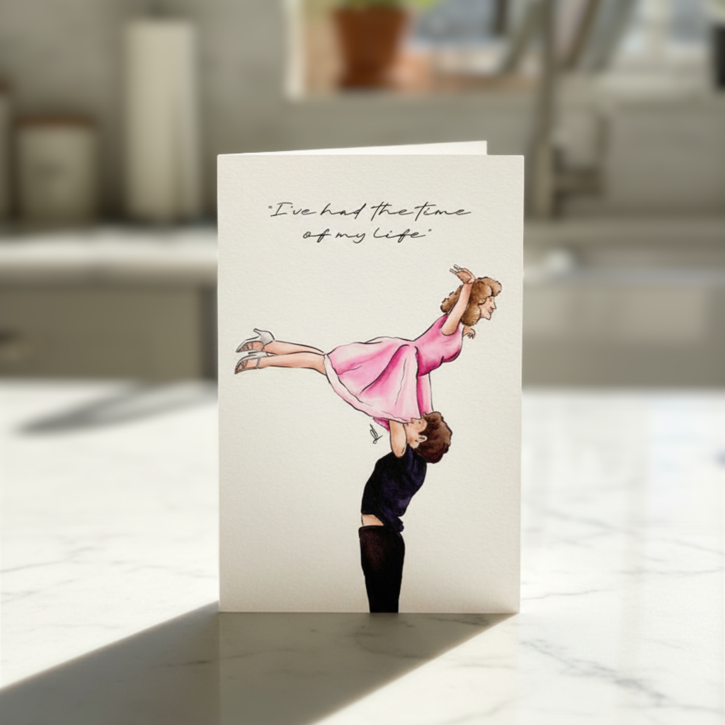 Greeting card with illustration of a man lifting a woman over his head and text 'I've had the time of my life' on a kitchen counter
