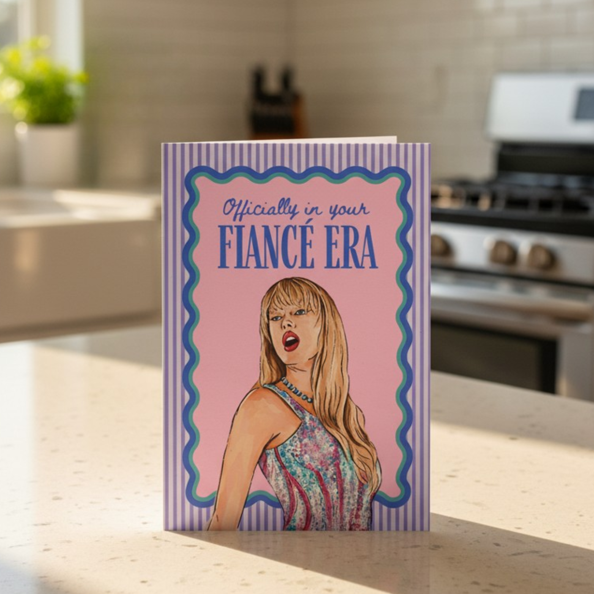 Card with a stylized illustration of a woman and text 'Officially in your FIANCE ERA' on a kitchen counter.
