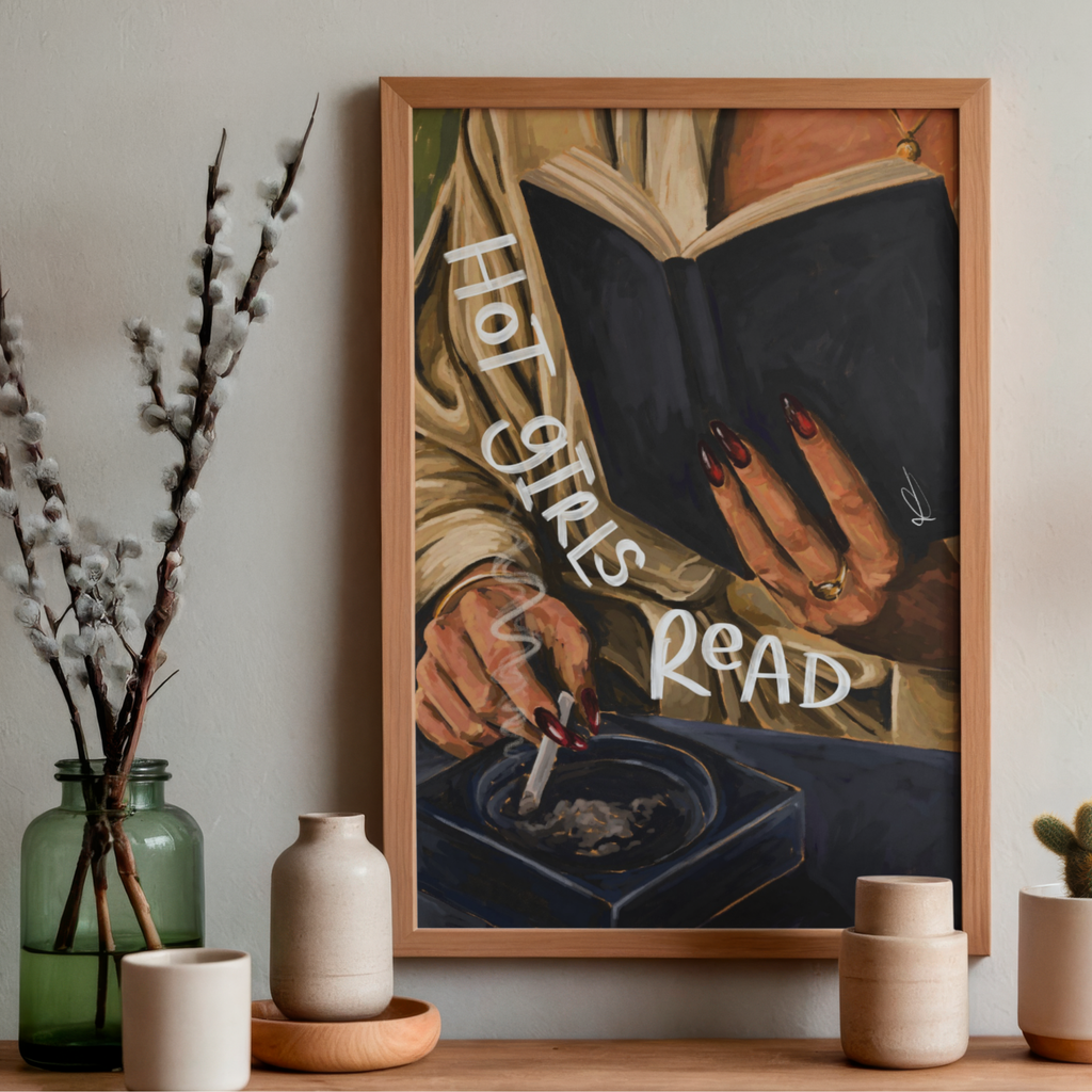 Framed art print of a woman reading whilst holding a cigarette with 'hot girls read' text, placed on a neutral wall