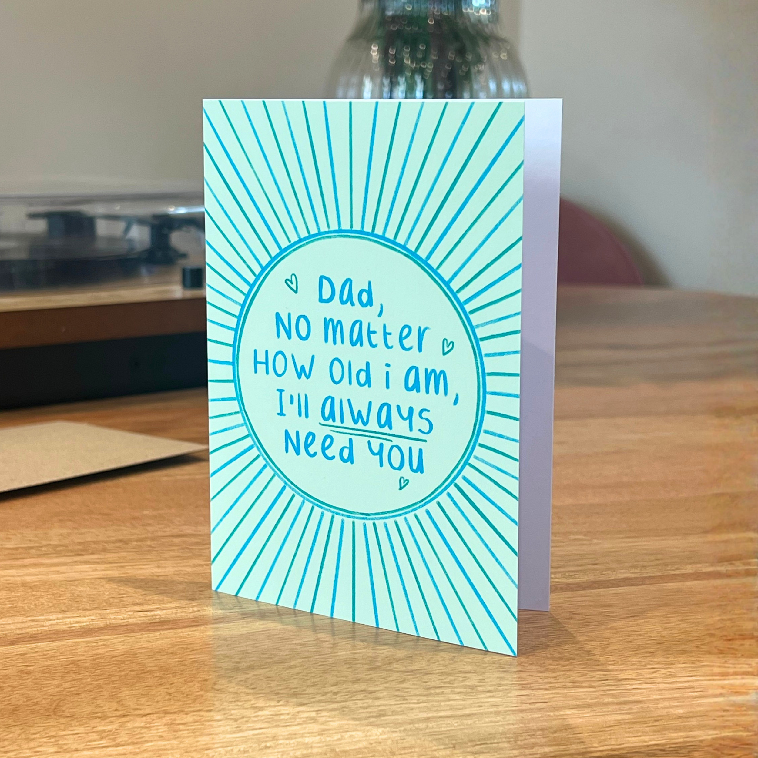 Father’s Day card with ‘no matter how old i am, I’ll always need you’ text on a wooden surface