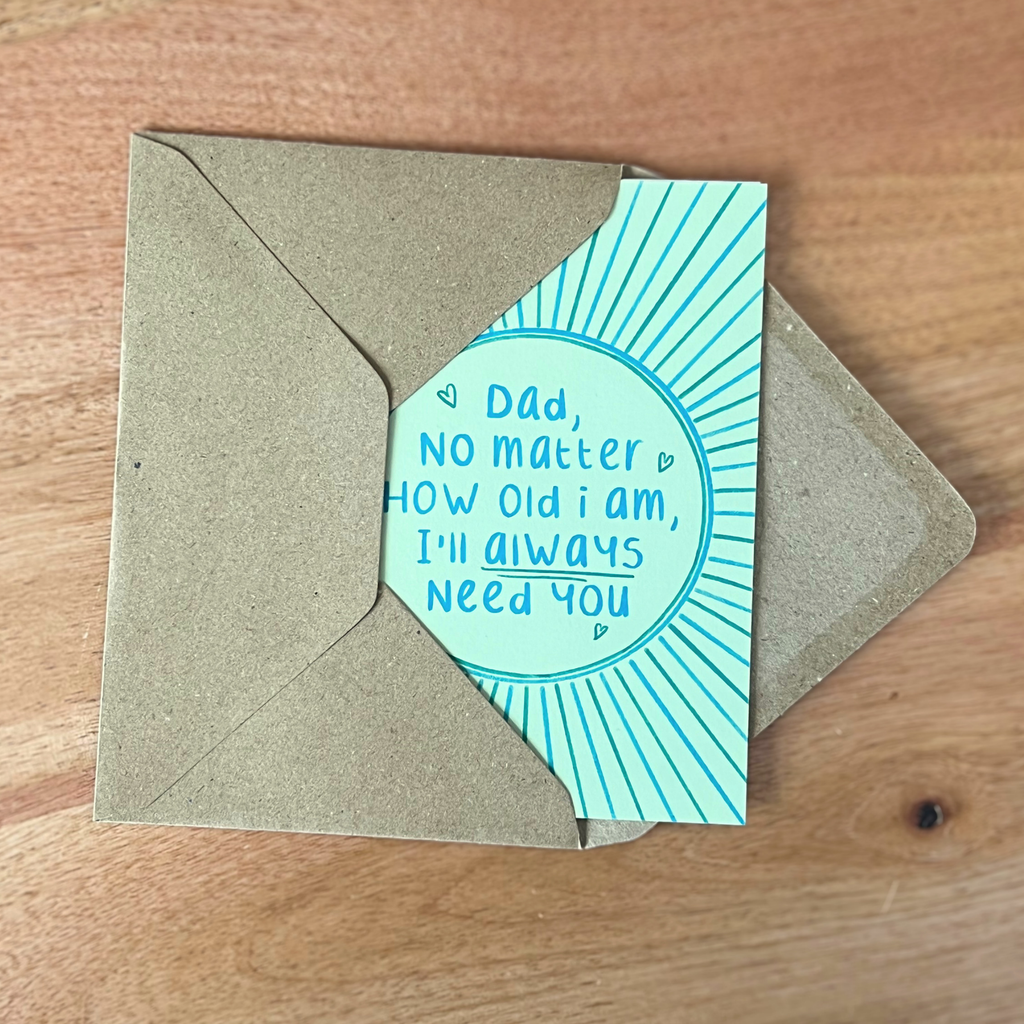 Card with message 'Dad, no matter how old I am, I'll always need you' on a wooden surface