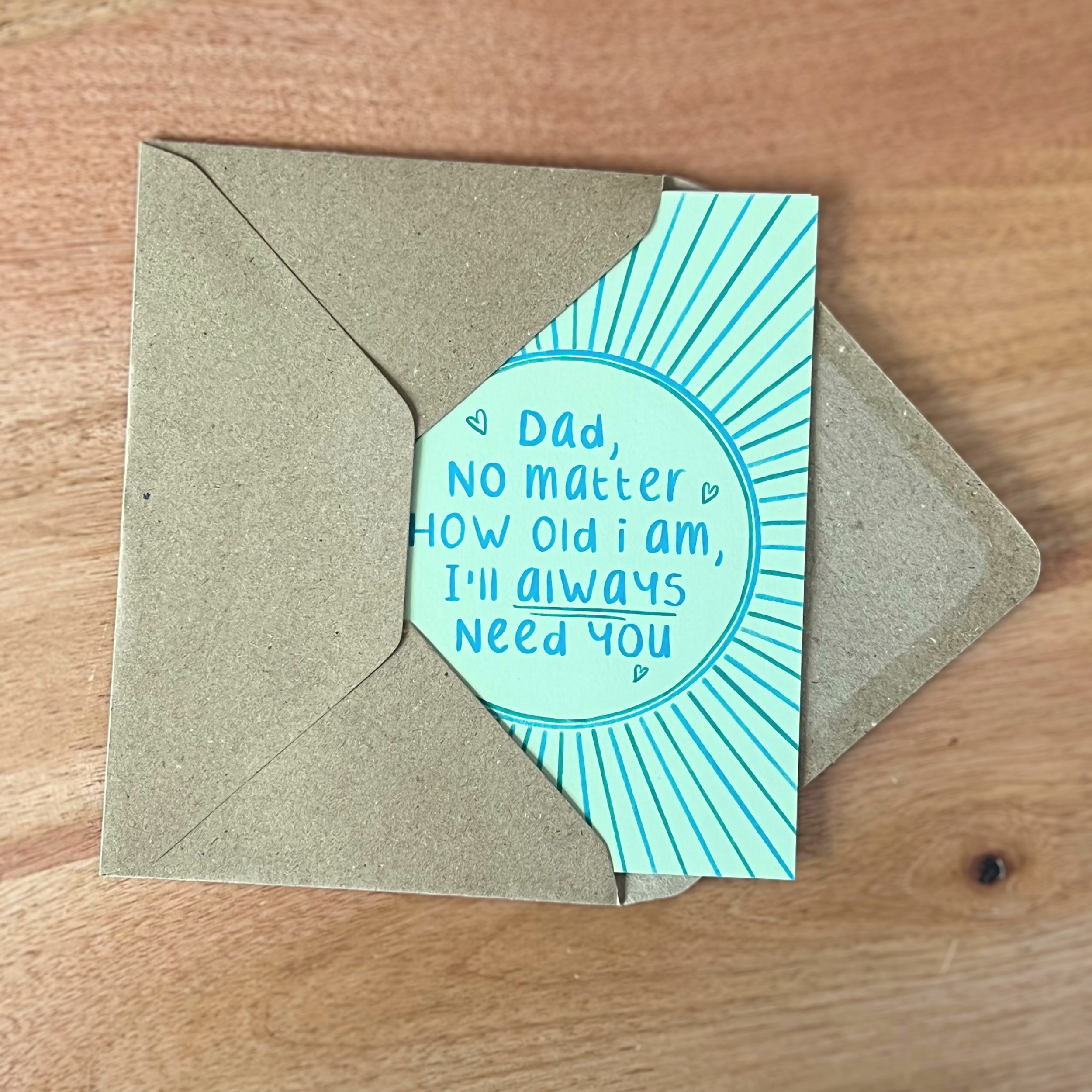 Card with message 'Dad, no matter how old I am, I'll always need you' on a wooden surface