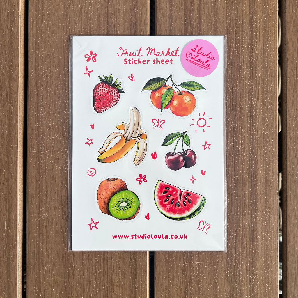 A fruit market themed sticker sheet featuring illustrations of strawberries, oranges, bananas, cherries, kiwi, and watermelon, displayed on a brown wooden background.