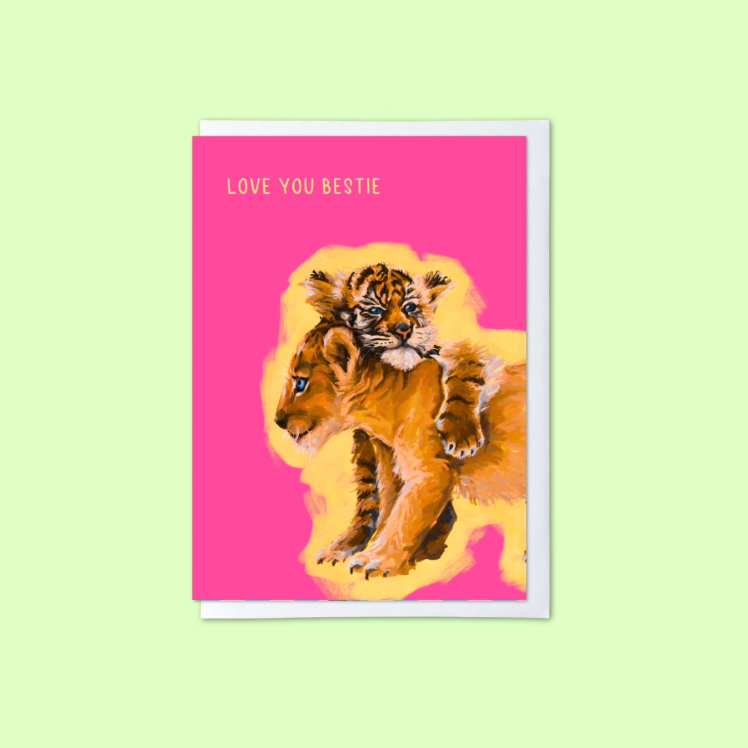 pink greeting card with lion and tiger cubs illustration and love you bestie message on a green background