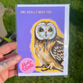 Card with an owl illustration and text 'OWL REALLY MISS YOU' held by a hand with a tattoo, against a blurred green background.