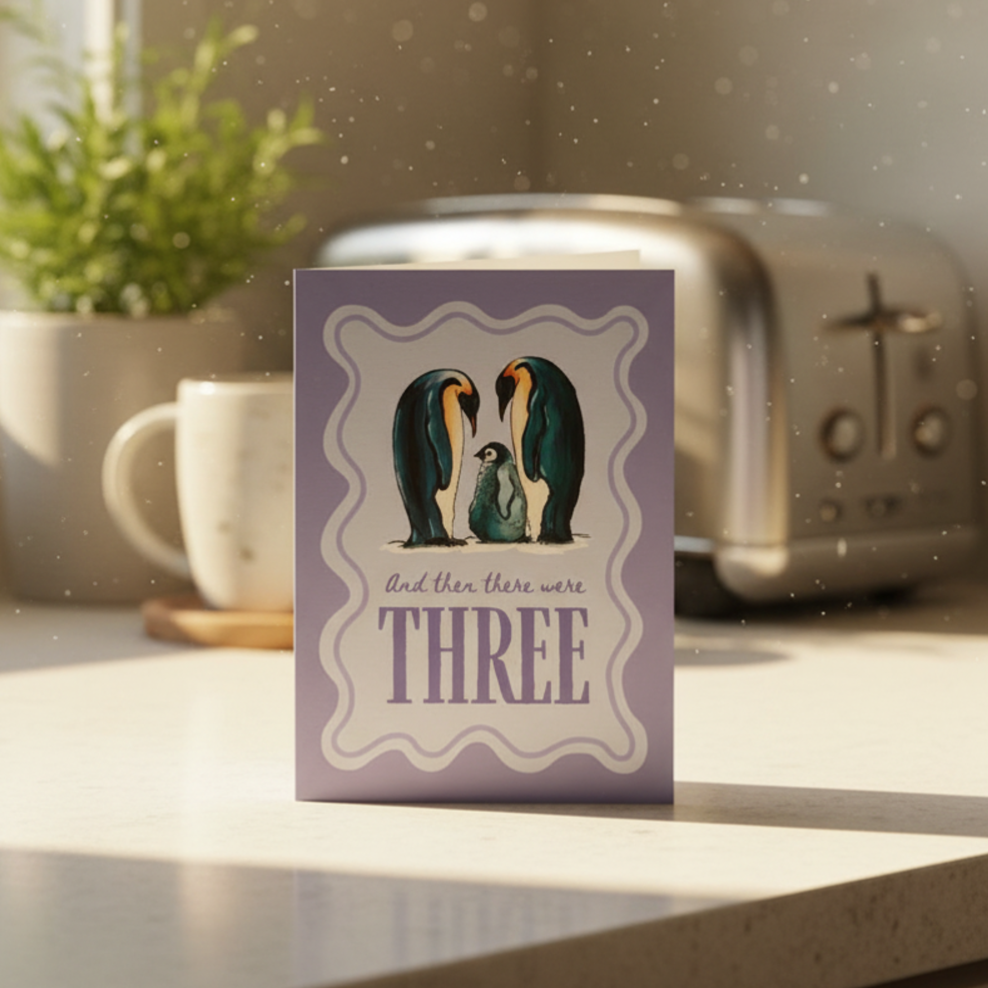 Card with penguin family illustration on a kitchen counter