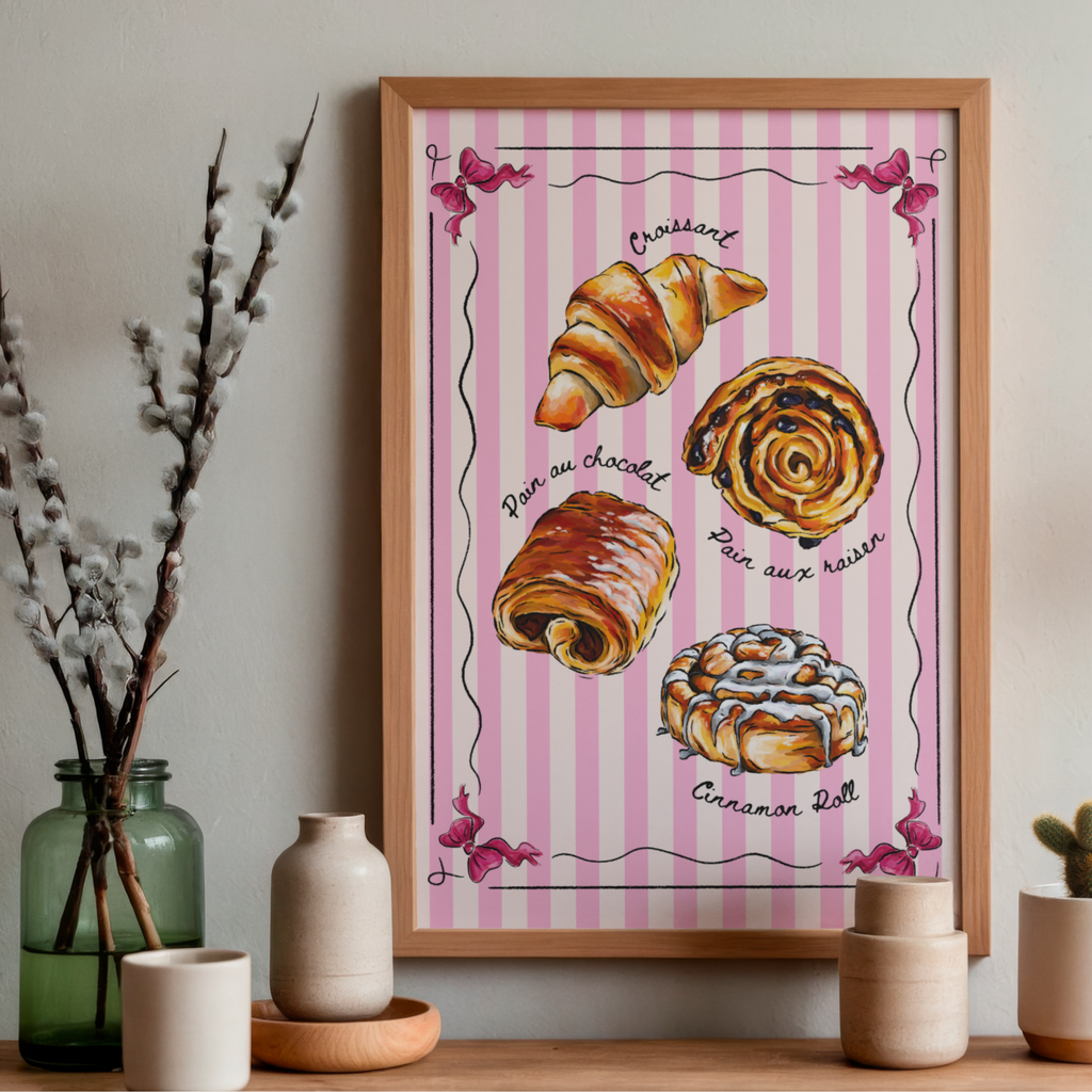 Framed artwork of pastries on a pink striped background, displayed on a wall with decorative items.