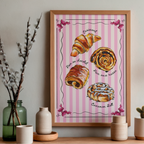 Framed artwork of pastries on a pink striped background, displayed on a wall with decorative items.