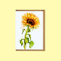 A vertical greeting card featuring a watercolor-style sunflower illustration on a white background, shown with a brown kraft envelope behind it against a pale yellow backdrop.