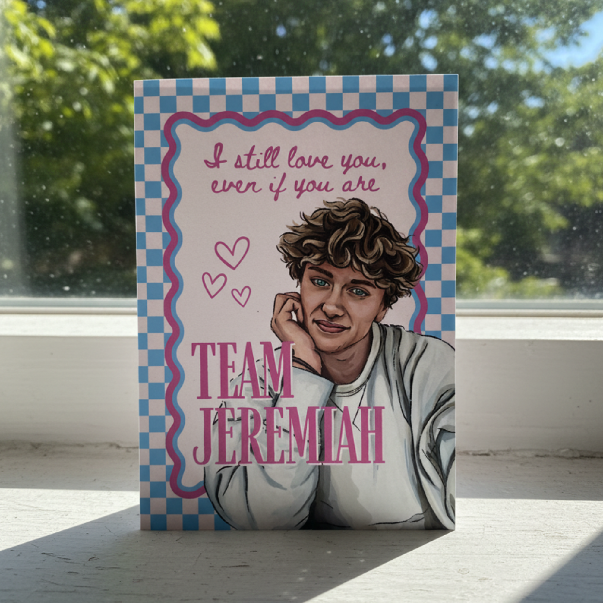 Card with illustration of a person and text 'I still love you, even if you are Team Jeremiah' on a checkered background.