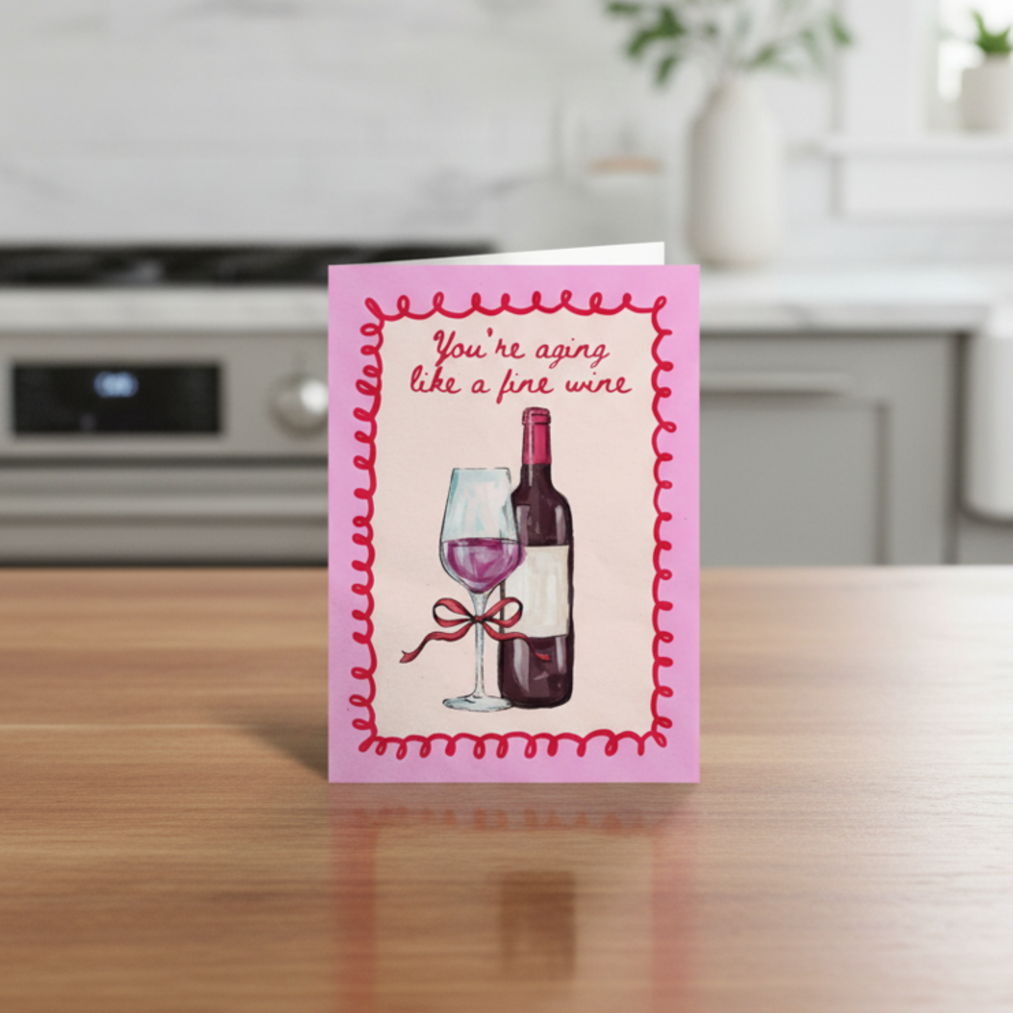 Greeting card with wine illustration and you’re aging like a fine wine text on a kitchen counter