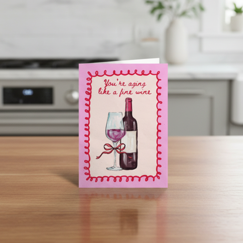 Greeting card with wine illustration and you’re aging like a fine wine text on a kitchen counter
